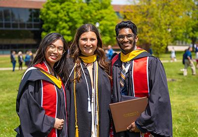 Three graduates sporting regalia.